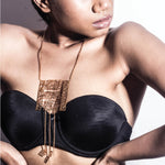 A person wearing a black top showcasing a gold-colored brass pendant necklace with intricate designs.